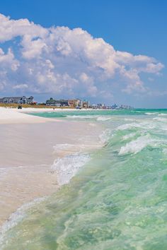 the ocean is green and white with waves coming in to shore on a sunny day