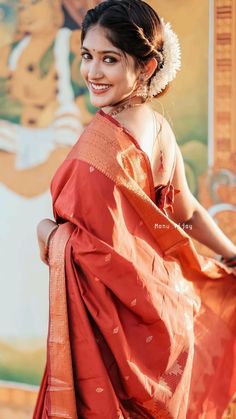 a woman in an orange sari is smiling