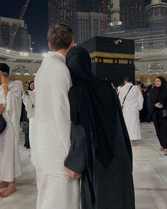 two men dressed in black and white standing next to each other at the ka'bah