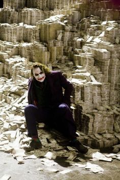 the joker is sitting in front of stacks of paper