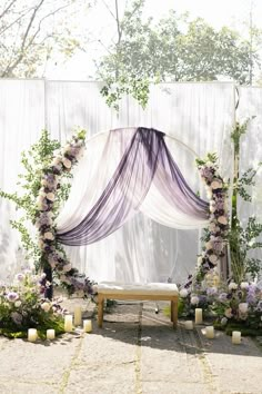 an outdoor ceremony setup with flowers and candles on the ground, surrounded by sheer curtains