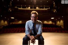 a man sitting on top of a chair in front of an empty auditorium