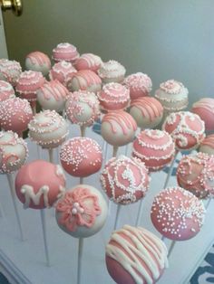 there are many pink and white cake pops on the stick