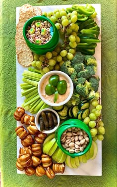 a platter filled with grapes, broccoli, nuts and other food items