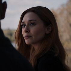 a close up of a person wearing a black shirt and looking at something in the distance