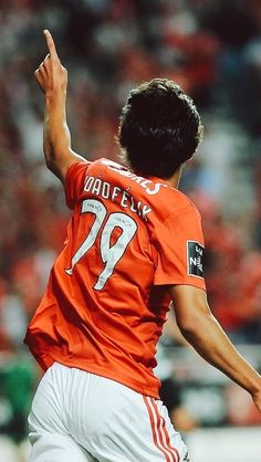 a soccer player in an orange shirt is kicking the ball with his hand and head