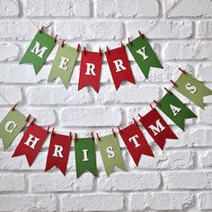 merry christmas bunting banner with red and green letters hanging from the side of a brick wall