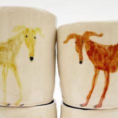 three coffee cups with different colored drawings on the outside and inside one cup has a dog, another is a giraffe