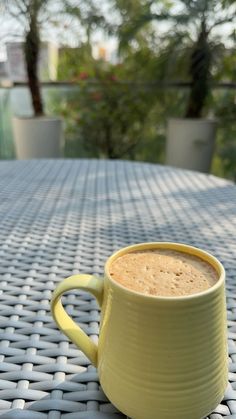 a yellow mug sitting on top of a table next to a cup of hot chocolate