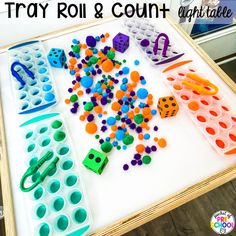 the tray is filled with different colored plastic toys and letters that spell out play roll & count