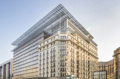 a large building with many windows on the side of it's face in front of other buildings