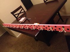 a wooden table topped with a pink and black polka dot ribbon on top of it