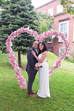 a bride and groom pose in front of a heart - shaped paper flower arrangement at their wedding