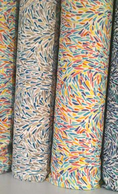 four rolls of multicolored paper are lined up on a shelf next to each other