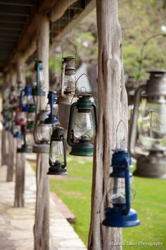 many lanterns are hanging from the side of a wooden structure in front of a grassy area