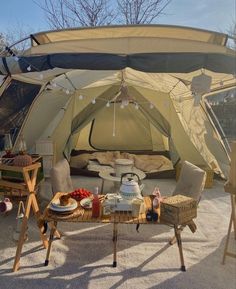 an outdoor tent set up with food and drinks on the table in front of it