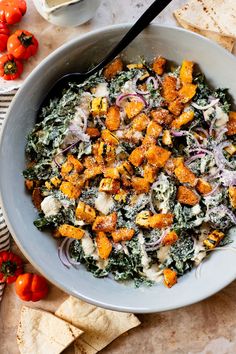 a white bowl filled with food next to tortilla chips and tomatoes on a table