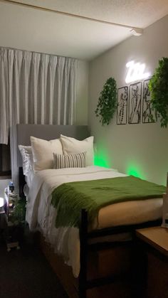 there is a bed with green lights on the headboard and pillows in this room