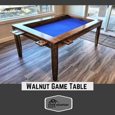 the walnut game table with blue felt is on display in an empty room next to a window