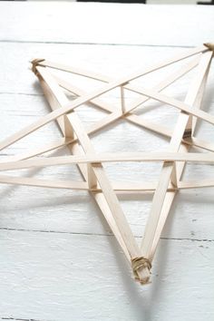 a wooden star ornament hanging on a white painted wall with string attached to it