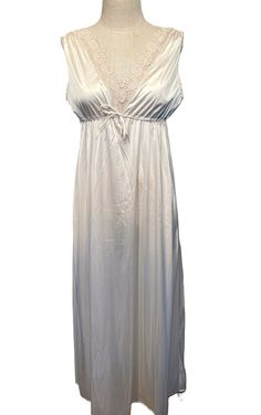 This lovely vintage nightgown is from the 1960s or early 70s. Labeled Mistee. No size tags. Bust measures 40", see measurements below.   Made of nylon in a champagne color. The gown slips over the head and sleeveless. Lace trims the arm openings and deep V neckline. It has a drawstring & tie at the empire waist. The gown reaches to the ankle.  Condition is very good.  No wear or stains. Charming! Measure yourself & know your measurements before buying! Please remember that vintage sizes run small. It is best to measure yourself, or a gown that fits you well. Measurements were taken with the garment lying flat. Measurements were taken without stretching.  Bust measured 2" below the underarms: 20" for a 40" or smaller bust Waist from side seam to side seam at the drawstring: 18" for a 36" or Beige Sleeveless Sleepwear For Wedding Night, Cream Sleeveless Nightgown, Sleeveless Cream Nightgown For Wedding, Sleeveless Cream Slip Dress For Sleep, Cream Sleeveless Slip Dress For Sleep, Cream Sleeveless Sleepwear For Wedding Night, Vintage Sleeveless Slip Dress For Loungewear, Vintage Sleeveless Slip Dress For Sleep, Cream Sleeveless Nightgown With Lace Trim