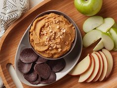 an apple and peanut butter snack on a wooden platter with sliced apples next to it