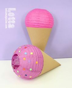 an ice cream cone with pink paper and sprinkles next to it on a table