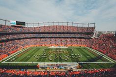 an orange and black football stadium with the marching band on it's sideline