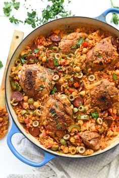 a blue skillet filled with chicken, rice and olives