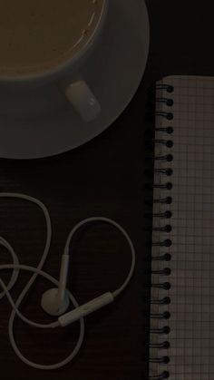 a cup of coffee and headphones sitting on a desk next to a notepad