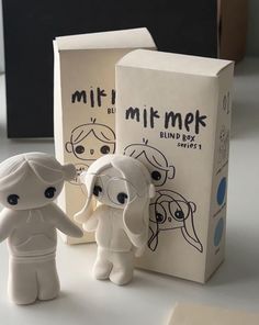 two little figurines are standing next to a box