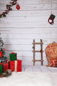 a christmas tree and presents in front of a white wall with wooden slatted boards