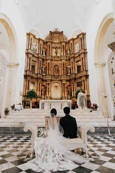 a bride and groom sitting on a bench in front of the alter at a church