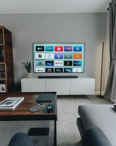 a flat screen tv sitting on top of a wooden table in a living room next to a window