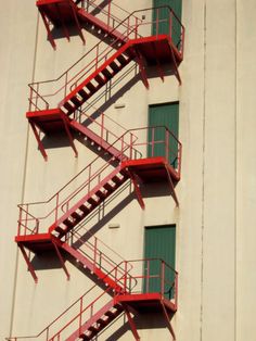 three red fire escapes on the side of a building