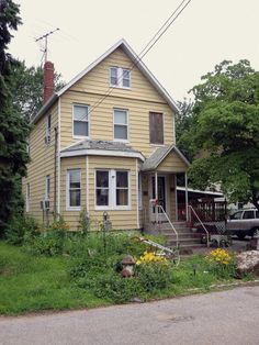 a yellow house sitting on the side of a road