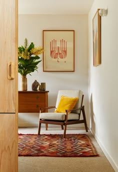 a room with a chair, rug and painting on the wall