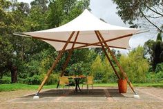 a large white tent set up in the middle of a park with tables and chairs under it