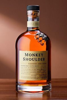 a bottle of monkey shoulderer on a table in front of a light brown background