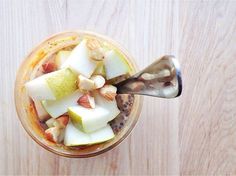 an overhead view of a smoothie with fruit and nuts in it on a wooden table