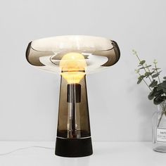 a table lamp sitting on top of a white counter next to a vase filled with flowers