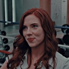 a woman with red hair and blue eyes is posing for a photo in the gym