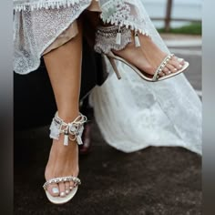 a bride's feet wearing high heeled sandals and white lace dress with beaded details