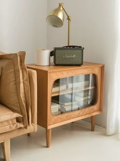 an old fashioned radio sitting on top of a wooden cabinet next to a chair and lamp