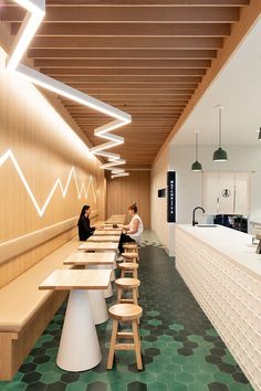 two women sitting at long tables in a restaurant with green flooring and white walls