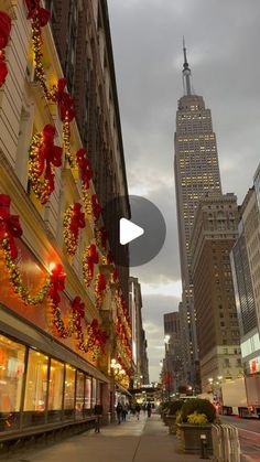 a city street filled with tall buildings covered in christmas decorations and lights on the side of it