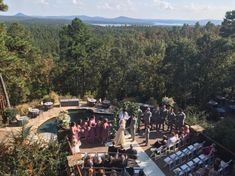 an aerial view of a wedding ceremony at the top of a hill in the woods