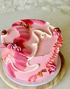 a pink cake with white frosting and flowers on it sitting on a marble platter