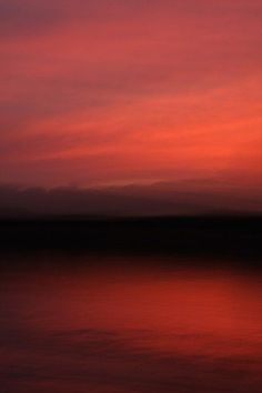 the sky is pink and orange as it reflects in the water