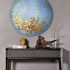 a table with a buddha statue on it and a blue circular wall hanging above it